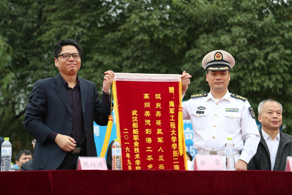 党委书记熊仕涛(左)代表学院向承训部队海军工程大学学员二旅赠送锦旗